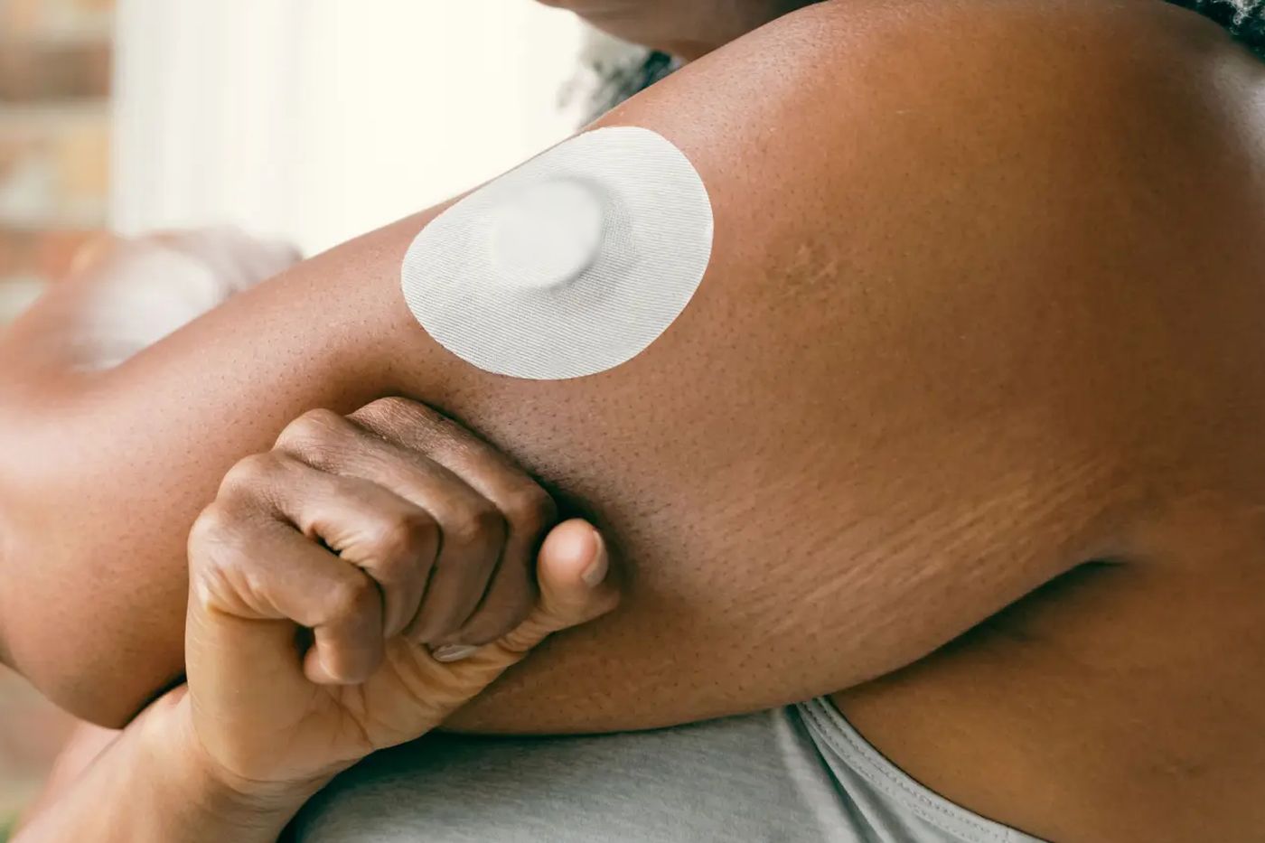 Capteur de glucose rond et blanc collé à l'arrière d'un bras
