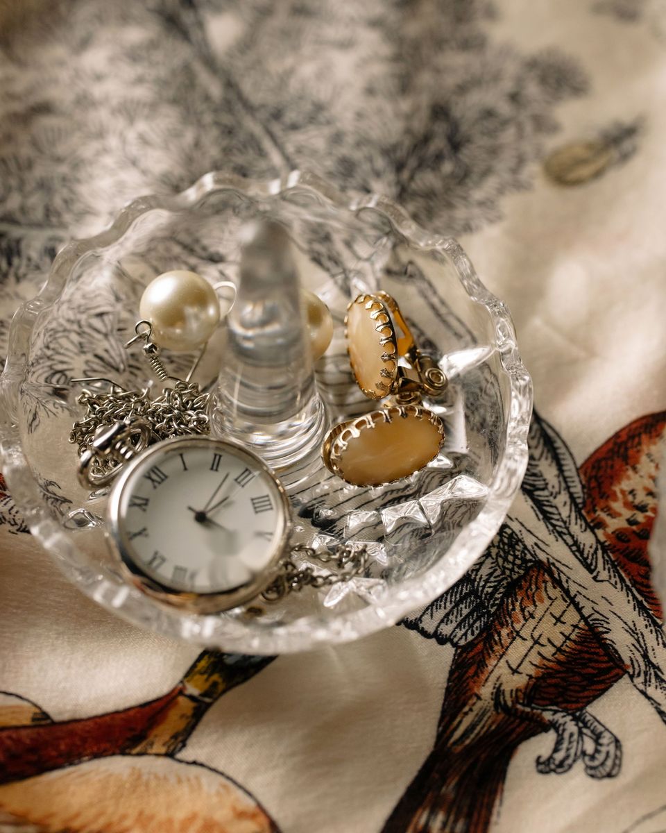 Coupelle en verre ciselé contenant une montre à gousset, des perles et des bijoux dorés