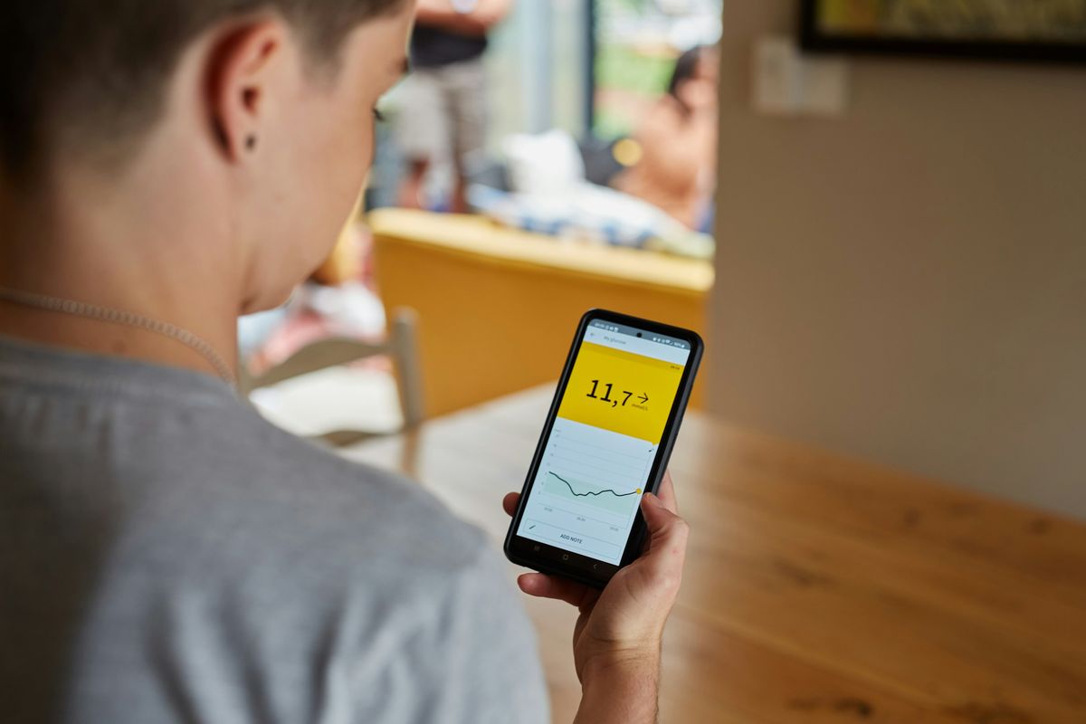 Personne vue de dos consultant sur son téléphone une courbe et une valeur affichées par l'application d'un capteur