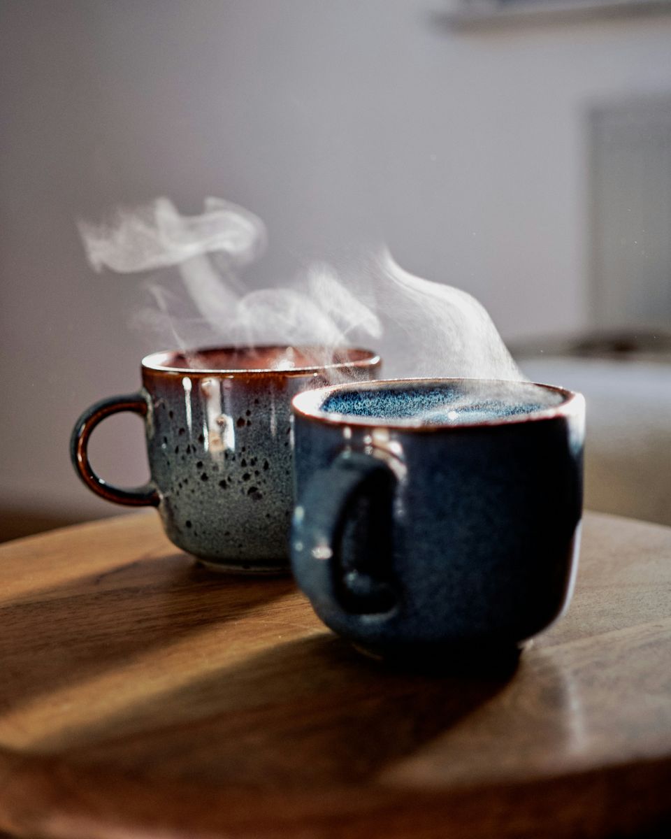 Deux tasses de café fumantes posées côte à côte sur une table en bois